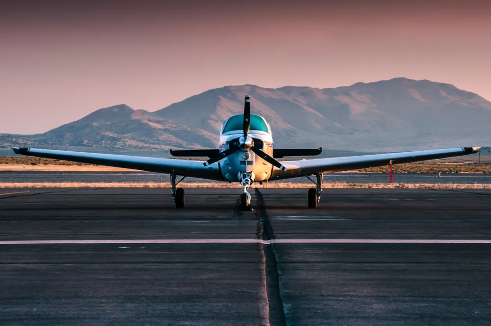 Small airplane on runway with mountain background